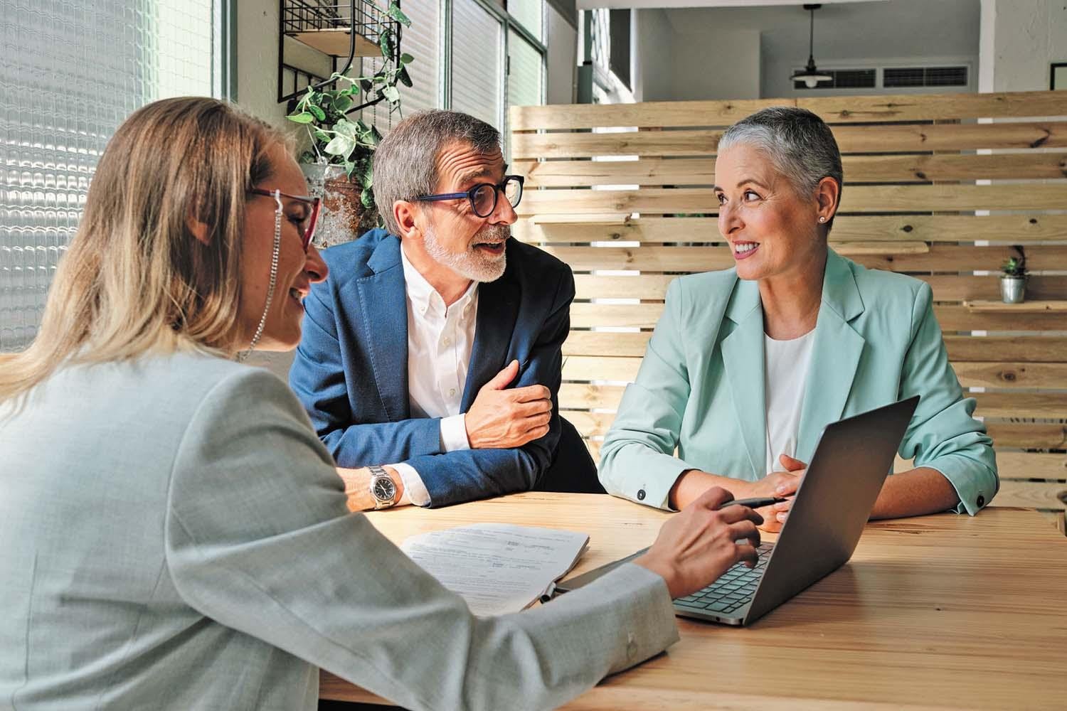 An insurance advisor reviewing coverage information with an older couple at their table